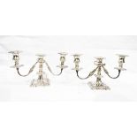 Pair of silver-plated two-branch candelabra with scroll supports on shaped square bases decorated