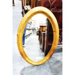 Large oval mirror within a carved oval frame and another mirror within a light wood arched frame