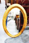 Large oval mirror within a carved oval frame and another mirror within a light wood arched frame