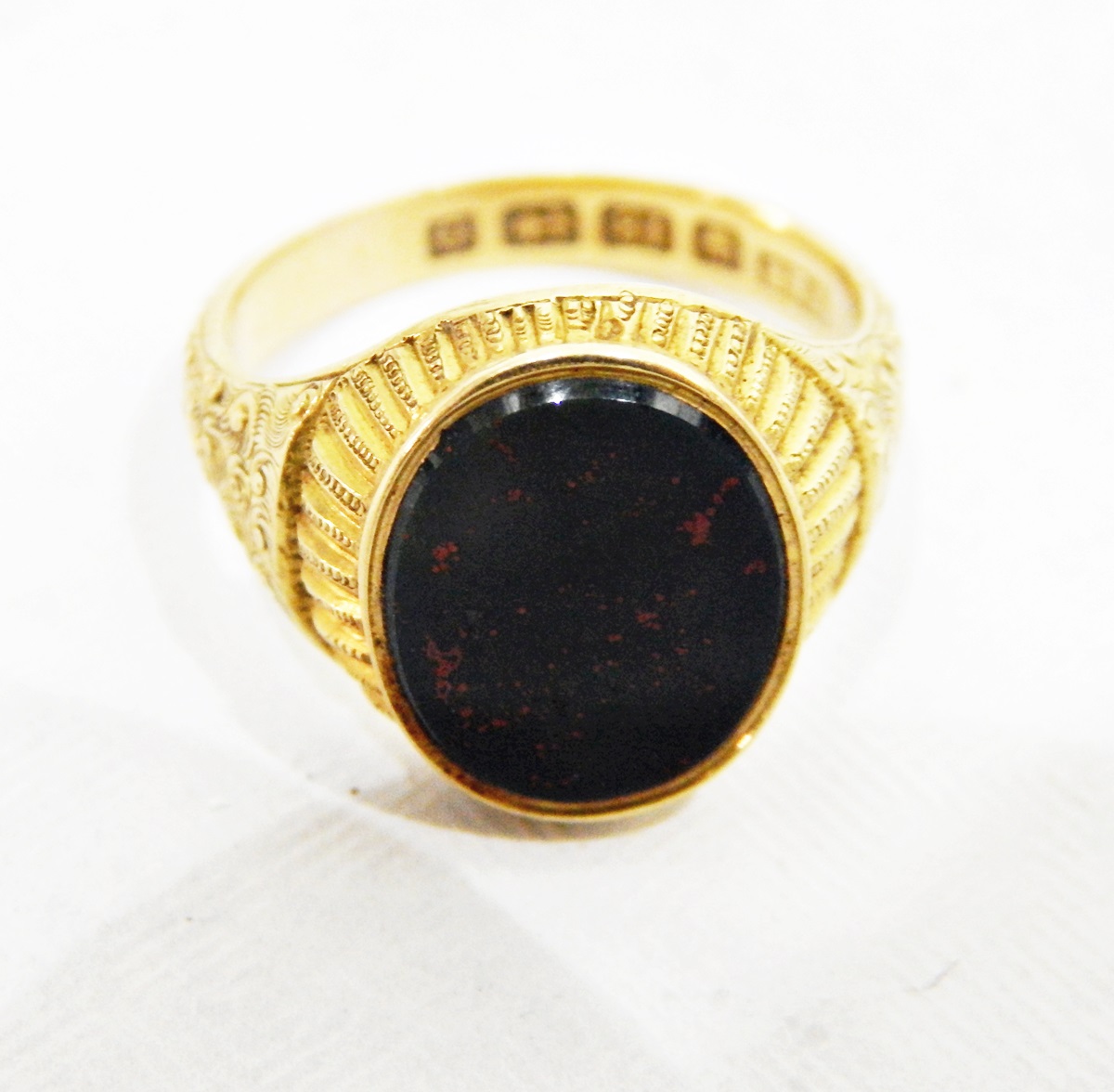 18ct gold and bloodstone signet ring, oval with fluted border and scroll engraved shoulders,