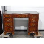 Serpentine-fronted reproduction mahogany kneehole desk, the top inset with green and gilt leather,