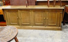Panamanian hardwood sideboard with fall-flaps enclosed by four doors with applied mouldings and on
