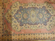 Wool rug with pale pink field, having shaped blue and cream arabesque to centre,