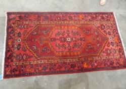 Persian wool rug with ruby red field, central herati and trailing stylised leaf borders,