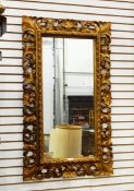 Carved giltwood wall mirror, rectangular, of rococo style with foliate openwork frame,