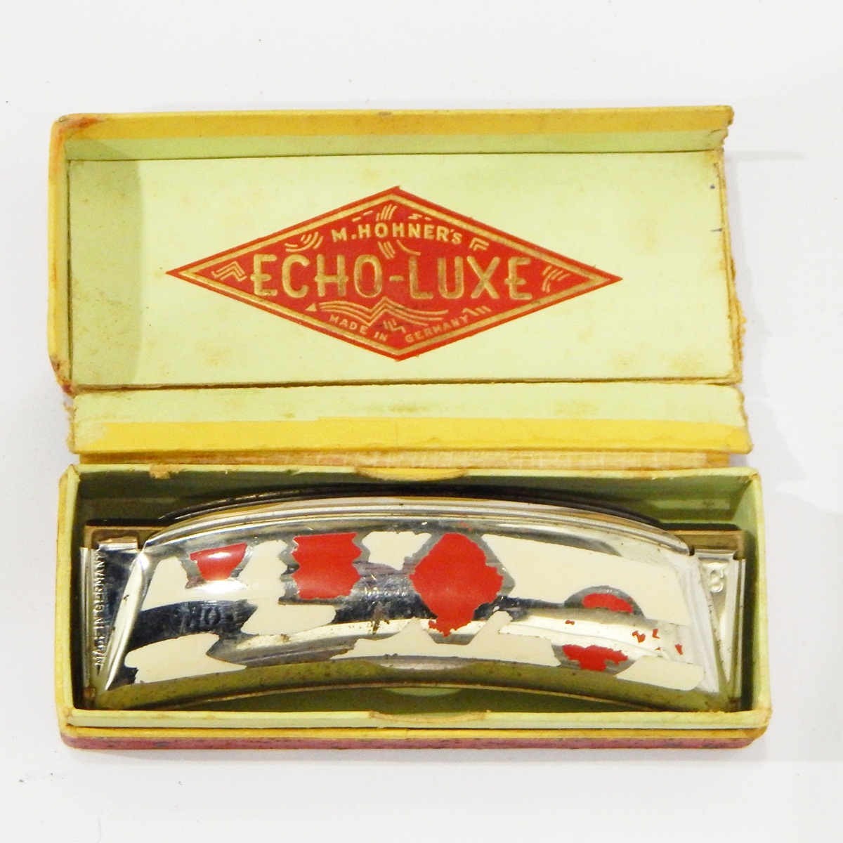 M Hohner Echo-Luxe harmonica, of crescent-shape with cream and red enamel decoration,