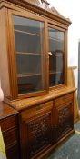 Edwardian walnut bookcase on cupboard having carved and shaped pediment over dentil cornice,