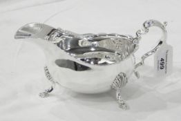 Contemporary silver sauceboat of Georgian design with ogee cut card borders and raised on three