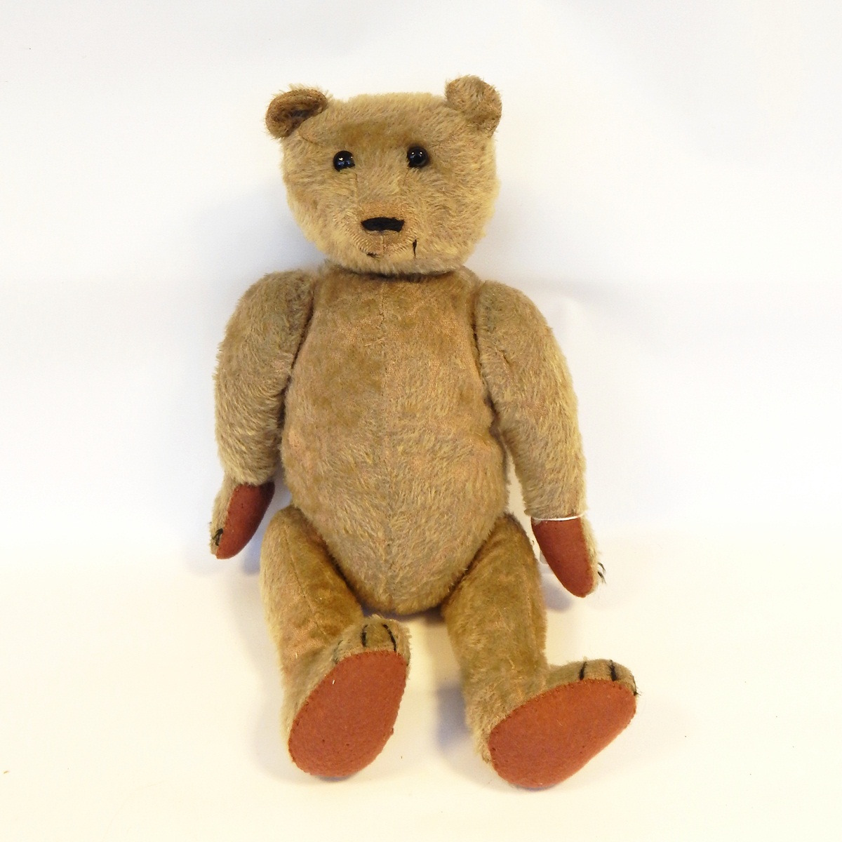 Old plush bodied teddy bear, straw filled, articulated limbs, hump back, glass bead eyes, sewn nose,