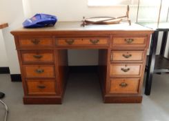 Edwardian oak kneehole pedestal desk having an arrangement of nine drawers with brass bale handles