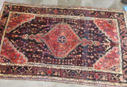 Eastern wool rug with midnight blue field and geometric ruby red arabesque to centre,