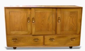 Ercol elm sideboard having slightly curved top, fitted three cupboards, with two drawers below,
