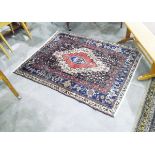Eastern wool rug, with central red medallion within blue and cream borders,