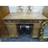 Pine kneehole pedestal desk having an arrangement of nine drawers and standing on turned bun feet,