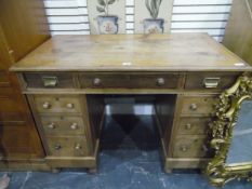 Pine kneehole pedestal desk having an arrangement of nine drawers and standing on turned bun feet,