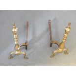 Pair of brass fire dogs, the knopped stems with urn finials,