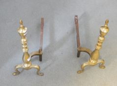 Pair of brass fire dogs, the knopped stems with urn finials,