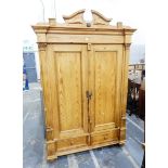 Continental style pine two-door wardrobe having shaped pediment over two panelled doors flanked by