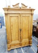 Continental style pine two-door wardrobe having shaped pediment over two panelled doors flanked by
