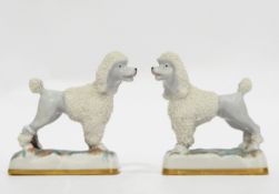 Pair of porcelain poodle models with gold anchor to base,