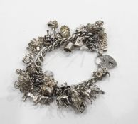 Heavy silver curb-link charm bracelet hung with numerous silver charms including articulated