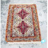 Eastern wool rug with two cherry red arabesques to the ivory field and having stylised leaf borders,