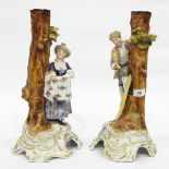 Pair of 19th century German porcelain figures beside tree trunks,