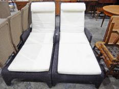 Two all-weather simulated cane sun loungers with mattresses and a pair of small tables with plate