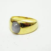 Gentleman's gold-coloured gemset ring, the central cabochon stone showing asterism,