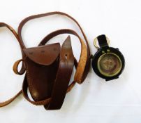 Military brass and black metal handheld compass in leather carrying case
