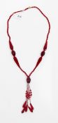 Vintage red glass bead necklace with faceted beads of varying shades of red and with central tassel