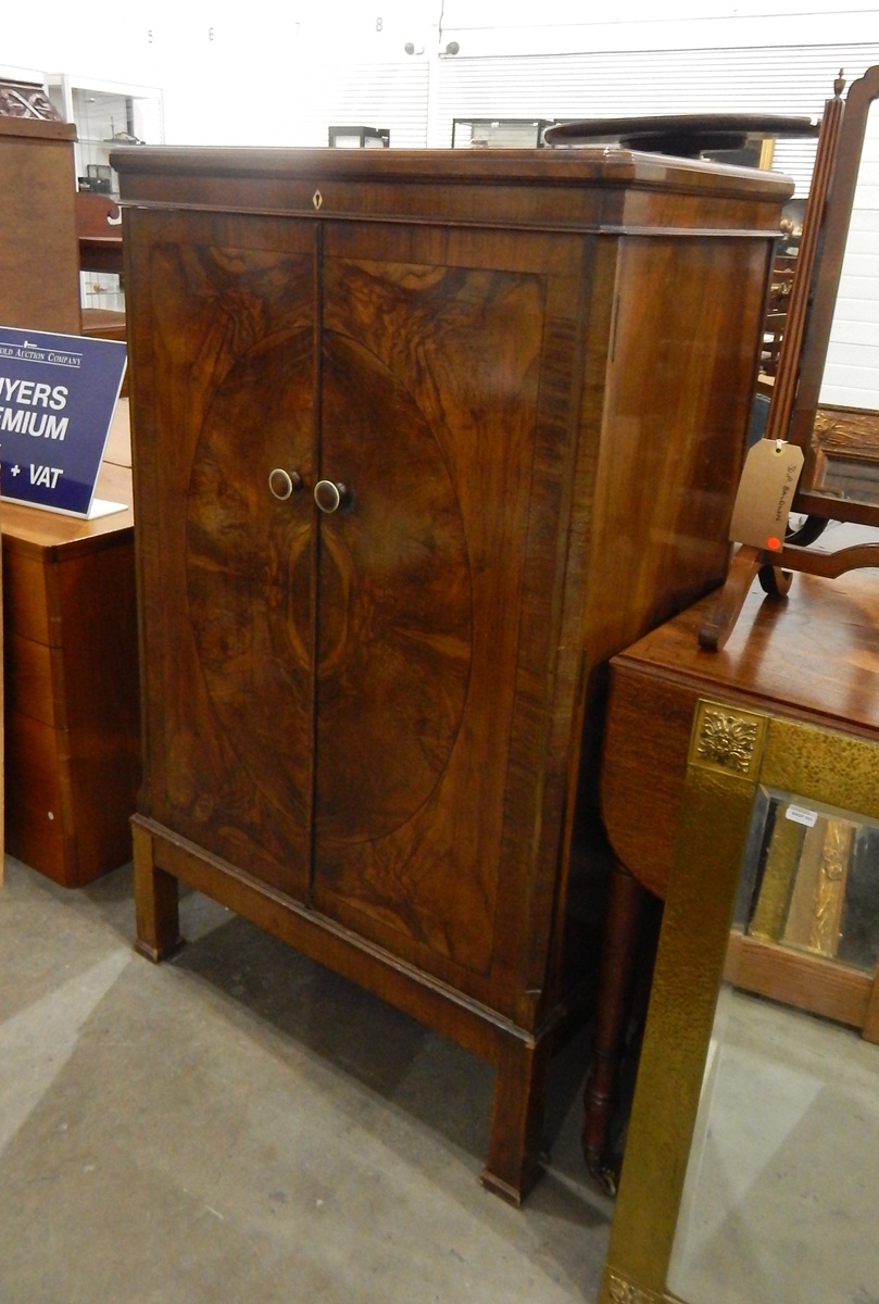 Walnut veneer cocktail cabinet, the rising top enclosing a fitted interior, with mirror back,