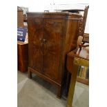 Walnut veneer cocktail cabinet, the rising top enclosing a fitted interior, with mirror back,