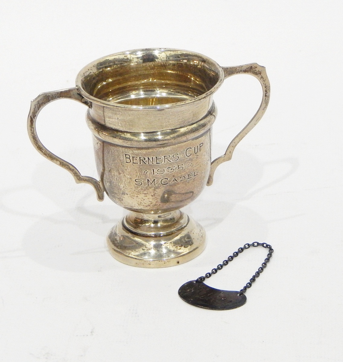 Silver two-handled trophy, Birmingham 1935 and a modern silver wine label for whisky,