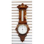 Aneroid barometer and thermometer in carved oak case with floral decoration columns and swan neck