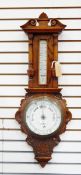 Aneroid barometer and thermometer in carved oak case with floral decoration columns and swan neck