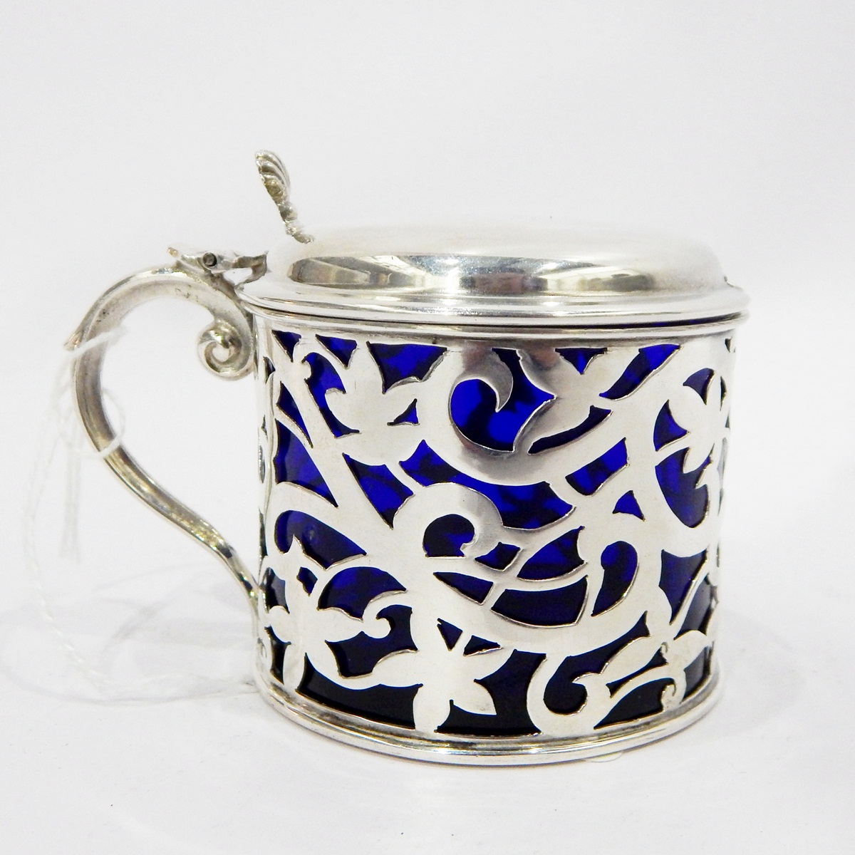Early 20th century silver mustard pot with blue glass liner, floral pierced decoration,