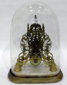 Brass skeleton clock under a glass dome, Roman numeral dial,
