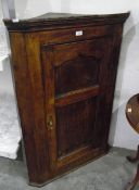 Early 19th century oak hanging corner cupboard enclosed by a two-panelled door,