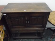 Reproduction dwarf oak cabinet enclosed by two linenfold panel doors over one long drawer and with