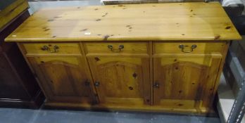 Modern pine sideboard having three drawers over three panelled doors and on plinth base,
