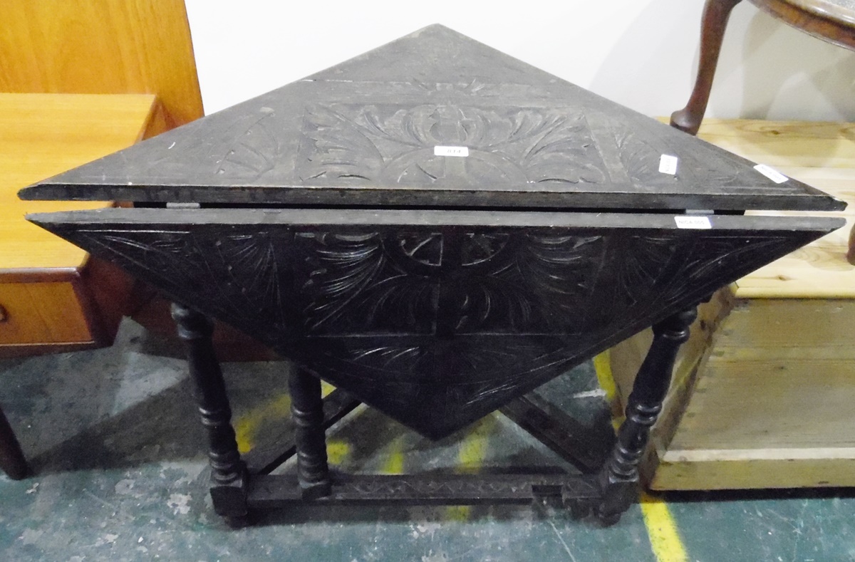 Dark stained carved oak envelope fall-flap table on turned supports