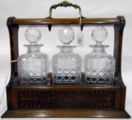 Early 20th century oak tantalus with three cut glass decanters,
