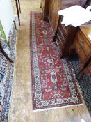 Old Persian wool runner, having octagonal framed stylised flowers, on a cherry red ground,