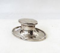 George V silver capstan inkwell of oval form, the hinged lid enclosing glass inkwell,