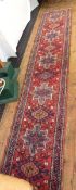 Iranian wool runner with star-shaped arabesques alternating with hooked lozenges to the cherry red