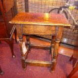 An antique oak joint stool raised on tur