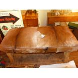 A rustic pine stool upholstered in goat