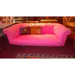 A Victorian Chesterfield sofa upholstered in buttoned pink fabric and raised on turned supports