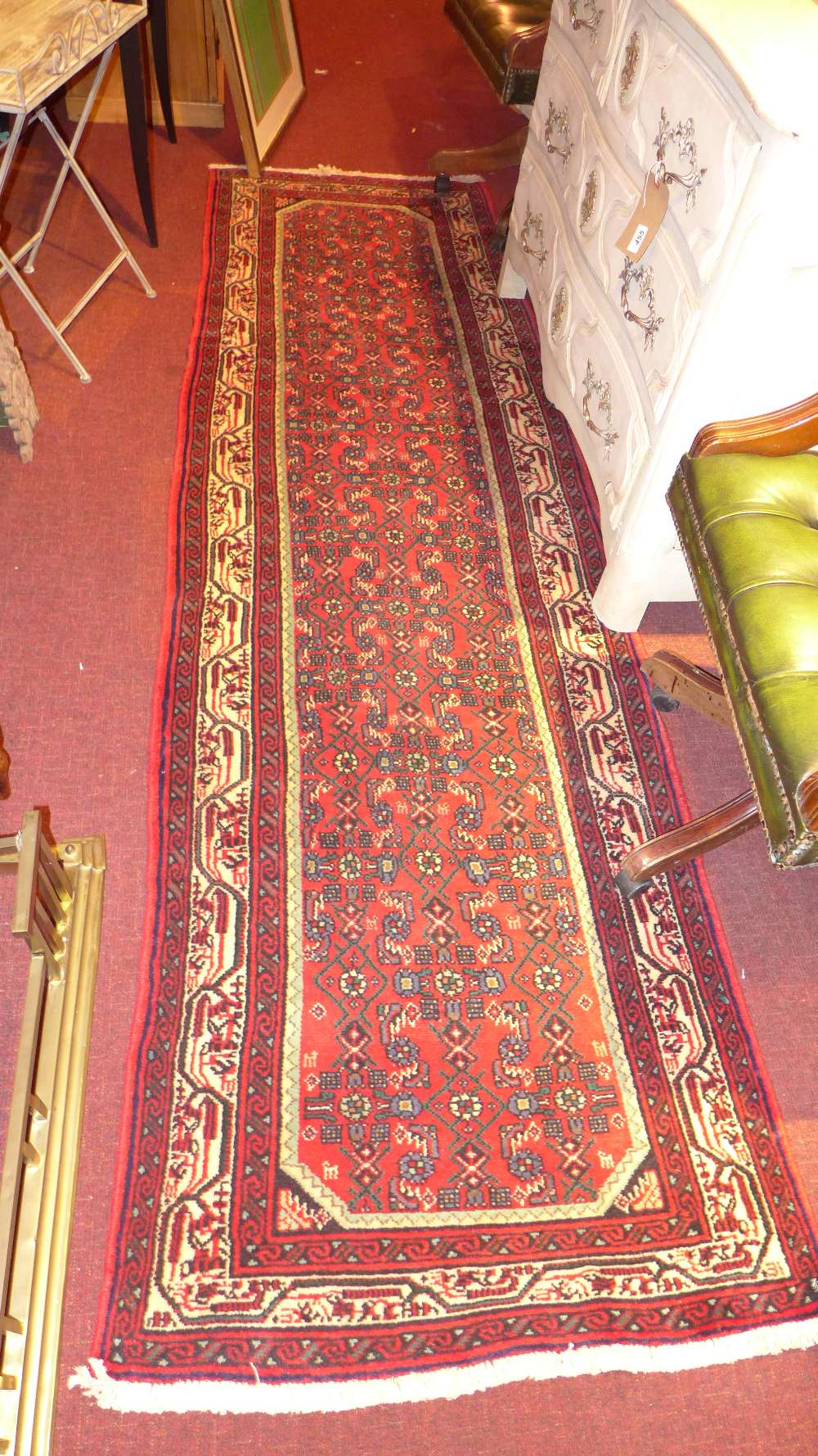 A fine north west Persian Malayer runner 285cm x 84cm with repeating Heratie motifs on a rouge field